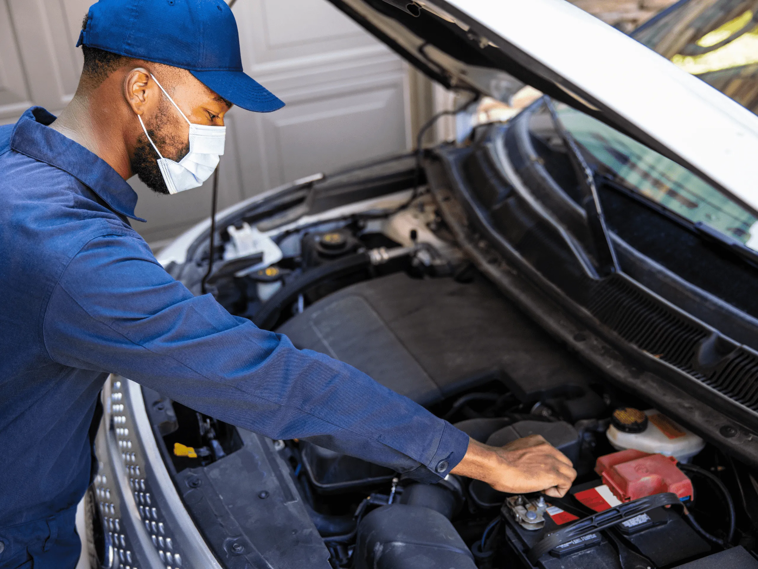 Mechanic checking the battery of a car with the bonnet open