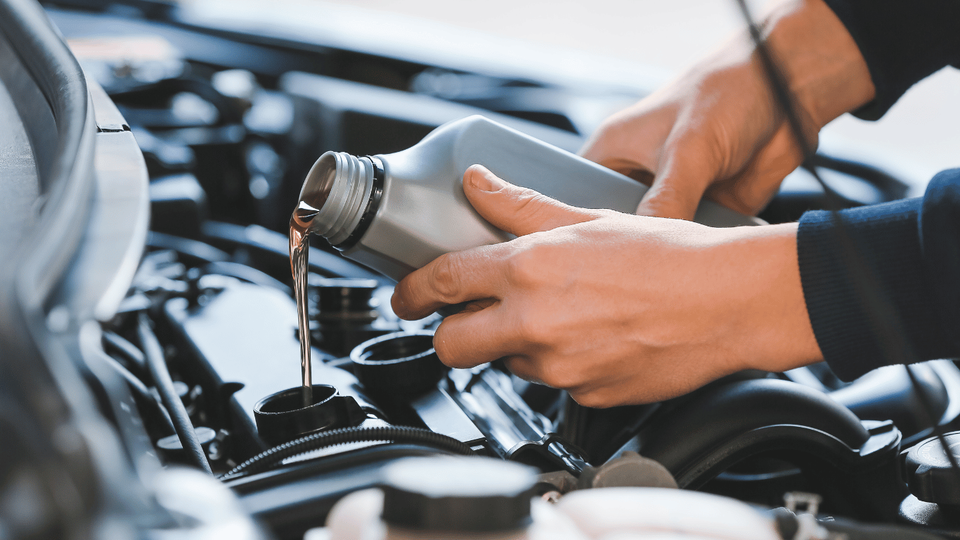 Person pouring oil into car