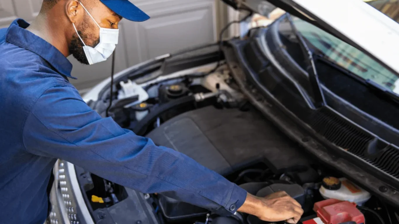 Mechanic checking the battery of a car with the bonnet open