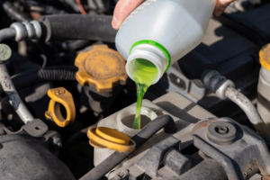 Green coolant being poured into car engine